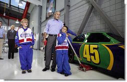 President George W. Bush gets a close-up view of the 45 car Wednesday, Oct. 18, 2006, at Victory Junction Gang Camp, Inc. with Will "Cheese" Kwapil, 12, left, who suffers from a congenital heart defect, and Pauly Rader, 9, who has a brain tumor. The camp, founded by Kyle and Pattie Petty, serves children primarily from North Carolina, South Carolina and Virginia with chronic medical conditions or serious illnesses.  White House photo by Paul Morse