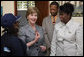 Mrs. Laura Bush, joined by Guerda Previlon, right, chief of party IDEJEN, and Gabriel Bienime, Haiti Education Minister, visits with a student enrolled in the IDEJEN educational program at the College de St. Martin Tours Thursday, March 13, 2008, in Port-au-Prince, Haiti. In an address to the faculty and staff Mrs. Bush said, “Educating its young people is one of the best things a country can do to ensure its continued development.” White House photo by Shealah Craighead