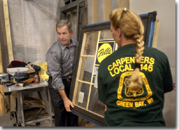 President George W. Bush assists a Union worker with the installation of a glass window frame during his tour of the Northern Wisconsin Regional Council of Carpenters Training Center in Kaukauna, WI., Monday, Sept. 3, 2001. WHITE HOUSE PHOTO BY ERIC DRAPER.
