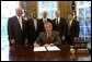 President George W. Bush signs an Executive Order implementing his Volunteers for Prosperity initiative in the Oval Office Thursday, Sept. 25, 2003. Pictured with the President are, from left: Deputy Secretary of Commerce Samuel W. Bodman; Deputy Secretary of Health and Human Services Claude A. Allen; Administrator, Agency for International Development, Andrew Natsios; Under Secretary of State Alan Larson; and Director, USA Freedom Corps, John Bridgeland. White House photo by Tina Hager