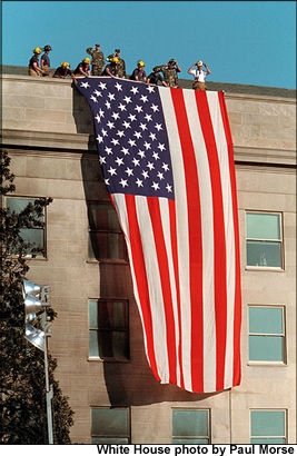 One day after terrorists used commercial airplanes to destroy the World Trade Center Towers and attack the Pentagon, firefighters take a moment to post the flag into the scarred stone as inspiration for fellow rescue workers searching through the debris Sept. 12. White House photo by Paul Morse.