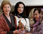 Mrs. Bush and two Afghan women standing in semi-circle; Mrs. Bush holds small wood carving of a man carrying a fish. 