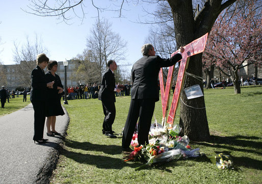 President George W. Bush signs a large Virginia Tech emblem, as the President and Mrs. Laura Bush stop to pay their respects at a campus memorial following the Convocation Tuesday, April 17, 2007 in Blacksburg, Va., honoring the shooting victims at Virginia Tech. The Bushes are accompanied by Governor Tim Kaine and his wife, Anne Holton. White House photo by Eric Draper
