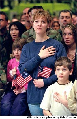 Family members of Air Force personnel place their hands over their hearts at Elmendorf Air Force Base in Anchorage, Alaska, Feb. 16, 2002. "I'm honored to be in a place where people understand the need for sacrifice and patriotism," said the President. "And I've come to Alaska to let you know that I'm proud of our United States military; that when I sent you into action, I knew you would not let this nation down.