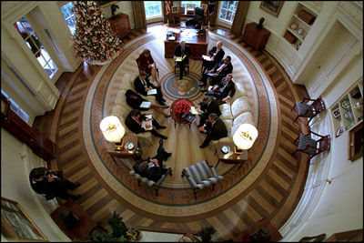 President George W. Bush hosts a meeting with senior advisers in the newly-renovated Oval Office, which includes a specially-designed wool rug featuring the Presidential coat of arms Dec. 20, 2001. The color scheme of the first Oval Office, built in 1909 during the Taft Administration, was olive green. 