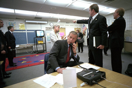 As Director of Communications Dan Bartlett points to news footage of the World Trade Center Towers burning, President George W. Bush gathers information about the attack at Emma E. Booker Elementary School in Sarasota, Fla., Sept. 11, 2001. Also photographed are Director of White House Situation Room, National Security Council, Deborah Loewer (directly behind the President) and Senior Advisor Karl Rove (right). White House photo by Eric Draper