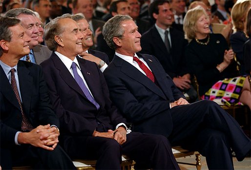 President George W. Bush sits with former Senator Bob Dole, center, and Mayor Stephen Goldsmith and watches the new public service announcement for the USA Freedom Corps in the East Room July 30. 
