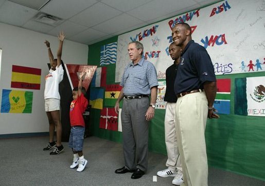 President George W. Bush watches an exercise class during a tour of Lakewest Family YMCA in Dallas, Texas, Friday, July 18, 2003. Also pictured, at far right, are Lynn Swann, Chairman of the President's Council on Physical Fitness and Sports and YMCA Volunteer Andrews Simpson. White House photo by Paul Morse