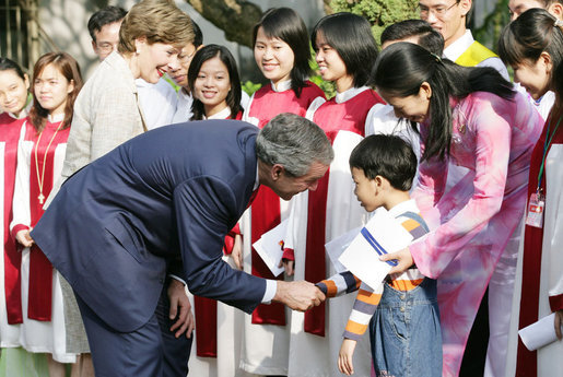 President George W. Bush and Mrs. Laura Bush pause to greet a young boy as they leave church services Sunday, Nov. 19, 2006, at the Cua Bac Church in Hanoi. White House photo by Shealah Craighead