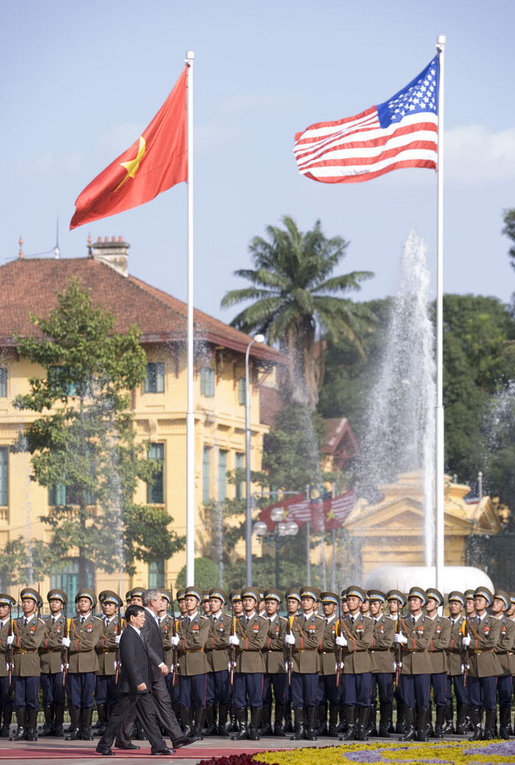 Under the American and Viet flags, President George W. Bush and President Nguyen Minh Triet review the honor guard during the arrival ceremony Friday, Nov. 17, 2006, in Hanoi. White House photo by Shealah Craighead