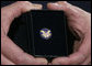 A White House military aide holds the President's Volunteer Service Award medal presented by President George W. Bush to military spouses Friday, May 11, 2007 at the White House, in honor of their outstanding volunteer service and to commemorate Military Spouse Day. White House photo by Eric Draper