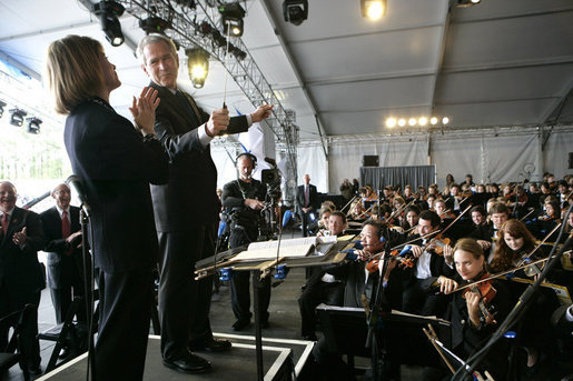 President George W. Bush looks toward conductor JoAnn Falletta as he directs the Virginia Symphony Orchestra Sunday, May 13, 2007, during the celebration marking the 400th anniversary of the Jamestown Settlement. White House photo by Eric Draper