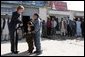 Laura Bush shows youngsters how to use a kaleidoscope outside a Kabul bakery after a stop Wednesday, March 30, 2005. The toys were gifts from the White House given by the first lady during her brief visit to Afghanistan. White House photo by Susan Sterner