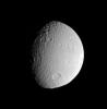 The Cassini spacecraft surveys the battered surface of icy Tethys. The great impact basin straddling the terminator is itself overprinted by many smaller impact sites