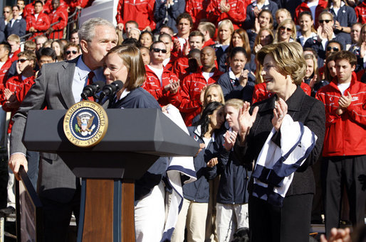 President George W. Bush kisses Army Lieutenant Melissa Stockwell, Paralympian and Iraq war veteran, after she presents President Bush and Mrs. Laura Bush with the American Flag that flew over the Olympic Village in Beijing following his remarks to members of the 2008 United States Summer Olympic and Paralympic Teams Tuesday, Oct. 7, 2008, on the South Lawn of the White House. White House photo by Eric Draper