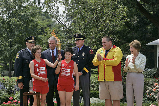 Runners Karen Dickerson of Springfield, Va., and Qiao Meili of Shanghai, China, hold up the lit torch during a Special Olympics Global Law Enforcement Torch Run Ceremony Thursday, July 26, 2007, in the Rose Garden. White House photo by Joyce N. Boghosian
