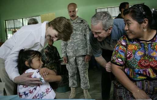 President George W. Bush and Mrs. Laura Bush play with a young girl during a visit Monday, March 12, 2007, to the Carlos Emilio Leonardo School in Santa Cruz Balanya, Guatemala. The couple visited a medical readiness and training exercise site at the school. White House photo by Eric Draper