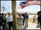 President George W. Bush watches as homeowner Jerry Akins places a flag outside his home Wednesday, March 8, 2006 in Gautier, Miss., on the site where the Akins family is rebuilding their home destroyed by Hurricane Katrina. White House photo by Eric Draper