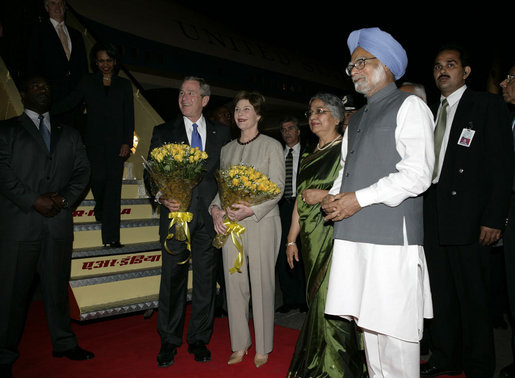 President George W. Bush and Mrs. Bush stand with flowers presented upon their arrival Wednesday, March 1, 2006, at New Delhi's Indira Gandhi International Airport where they were greeted by India's Prime Minister Manmohan Singh, right, and his wife, Gursharan Kaur. White House photo by Eric Draper