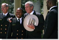 President George W. Bush is presented a cowboy hat and a Commander-in-Chief Trophy ring by Co-Captains Reggie Campbell, left, and Irv Spencer Monday, April 14, 2008, during the presentation of the Commander-in-Chief's Trophy to the United States Naval Academy Football Team in the Rose Garden at the White House. White House photo by Noah Rabinowitz