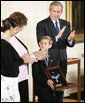 Young David Smith holds his father's Medal of Honor -- presented by President Bush -- as he looks to his mother, Birgit Smith, during ceremonies Monday, April 4, 2005, at the White House. Sgt. 1st Class Paul Smith, was mortally wounded while saving other members of his task force during Operation Iraqi Freedom.White House photo by Paul Morse