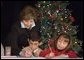 Laura Bush writes a note on a child's letter to his parent who is serving overseas, as she visits with children at the Naval and Marine Corps Reserve Center in Gulfport, Miss., Monday, Dec. 12, 2005, showing them a White House holiday video featuring the Bush's dogs "Barney and Miss Beazley." White House photo by Shealah Craighead