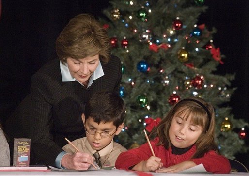 Laura Bush writes a note on a child's letter to his parent who is serving overseas, as she visits with children at the Naval and Marine Corps Reserve Center in Gulfport, Miss., Monday, Dec. 12, 2005, showing them a White House holiday video featuring the Bush's dogs "Barney and Miss Beazley." White House photo by Shealah Craighead