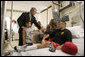 President George W. Bush holds the hand of Elvira Flores, wife of Lance Cpl. Alberto Flores, as their son A.J., watches during the President's visit Friday, July 1, 2005, to Walter Reed Army Medical Center. Lance Cpl. Flores, from Salinas, Calif., is being treated for injuries received while serving in Operation Iraqi Freedom. White House photo by Eric Draper