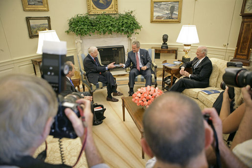 President George W. Bush accepts a report from former President Jimmy Carter and Secretary of State James Baker, Co-Chairs of the Carter-Baker Commission on Federal Election Reform, in the Oval Office Monday, Sept. 19, 2005. White House photo by Eric Draper