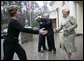 President George W. Bush and Russia President Vladimir Putin embrace in the background as Mrs. Bush reaches out to Lyudmila Putina, Russia's first lady, as the Bushes arrived Sunday, May 8, 2005, at the Putin residence shortly after their arrival in Moscow. White House photo by Eric Draper