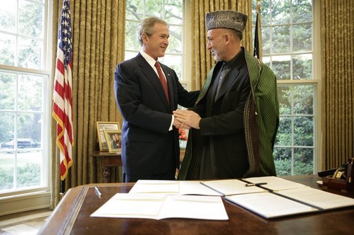 President George W. Bush and President Hamid Karzai of Afghanistan, shake hands Monday, May 23, 2005, in the Oval Office of the White House after signing a joint declaration that commits both the United States and Afghanistan to closely work together to enhance Afghanistan's long-term democracy, prosperity and security. White House photo by Eric Draper