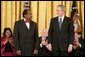 President George W. Bush exchanges a glance with Paul Rusesabagina during the presentation of the Presidential Medal of Freedom in the East Room Wednesday, Nov. 9, 2005. Paul Rusesabagina demonstrated remarkable courage and compassion in the face of genocidal terror. During the Rwandan genocide in 1994, he risked his own life to shelter more than 1,000 fellow Rwandans targeted for murder. White House photo by Paul Morse