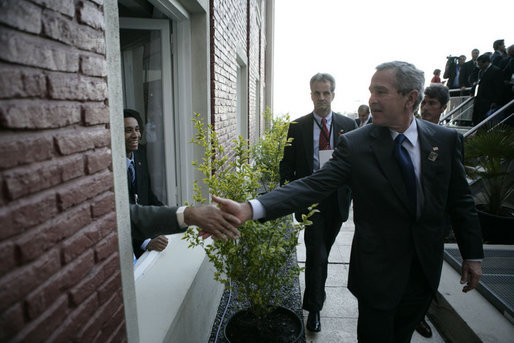 President George W. Bush reaches out for the hand of a well-wisher after participating in the 2005 class photo during opening ceremonies Friday, Nov. 4, 2005, of the Summit of the Americas in Mar del Plata, Argentina. White House photo by Eric Draper