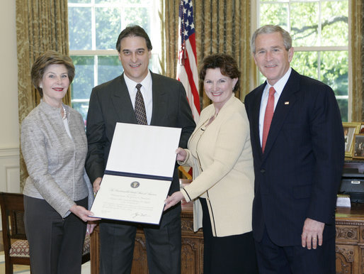 President George W. Bush and Mrs. Bush present the Preserve America award for private preservation to Judy Christa-Cathey, Vice President Brand Management, and Scott Douglas Schrank, Vice President Brand Performance and Support, both of Hampton Hotels' nationwide Save-A-Landmark program, in the Oval Office Monday, May 1, 2006. White House photo by Eric Draper