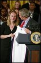 President George W. Bush stands with Maria Conlon of the University of Connecticut women's basketball team during a ceremony in the East Room congratulating four NCAA teams for winning national titles Wednesday, May 19, 2004. White House photo by Paul Morse.