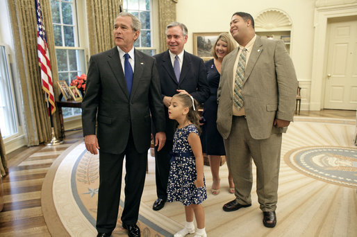 President George W. Bush and 5-year-old Alexa Ostolaza, the 2006 March of Dimes National Ambassador, peek out an Oval Office window for the President's dogs Thursday, July 6, 2006. With them, from left, are Jim Sproull Jr., Chairman of the Board of the March of the Dimes, and Alexa's parents Jessica and Josue Ostolaza. White House photo by Kimberlee Hewitt