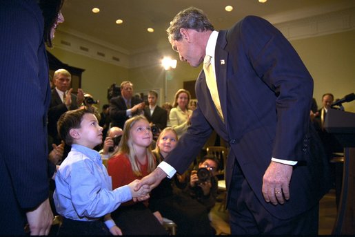 President George W. Bush talks to Solveig Haugen, her twin sister Liv and their younger brother Tad, after the signing of the Dot Kids Implementation and Efficiency Act of 2002 in the Roosevelt Room, Dec 4. The Haugen family of Loudoun County, Virginia is one family that will benefit from the act. The bill creates a second level Internet domain (kids.us), within the United States country code, that will provide a safe online environment for children ages 13 and under. White House photo by Eric Draper.