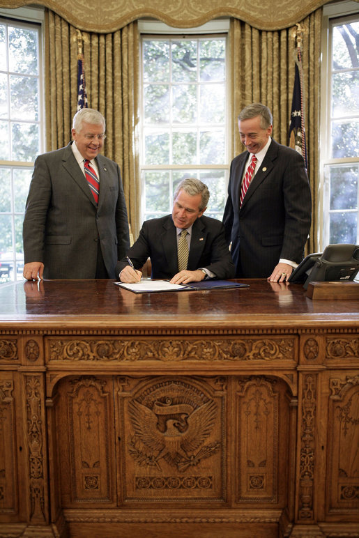 President George W. Bush signs S. 418, The Military Personnel Financial Services Protection Act, in the Oval Office Friday, Sept. 29, 2006. Standing with President Bush are bill sponsors Senator Mike Enzi, R-Wyo., left and Representative Geoff Davis, R-Ky. The legislation protects America’s armed forces by banning unscrupulous companies from military bases. It also prohibits the selling of life insurance products military personnel and their dependents unless specified written disclosures have been provided. White House photo by Eric Draper