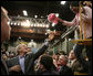 President George W. Bush reaches up to grab a worker’s cap to autograph it during his tour of the Caterpillar Inc. facility in East Peoria, Ill., Tuesday, Jan. 30, 2007. White House photo by Paul Morse