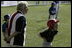 A runner with the Hamilton Little Lads of Hamilton, N.J., waits to make her next move with her honorary base coach Dolly White, former fielder with the Fort Wayne Daises and the Kenosha Comets, during the last game of the 2003 White House South Lawn Tee Ball season Sunday, Sept. 7, 2003. Ms. White played professional baseball with the All-American Girls Professional Baseball League Players Association, which operated from 1943 to 1954.