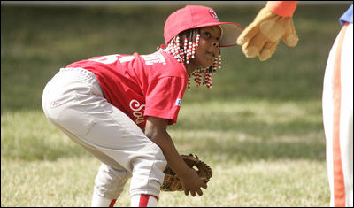 Taylor Paige Nevils of South Side Little League Memphis Red Sox from Chicago, peers up at Dugout, the Little League mascot, during a T-ball game on the South Lawn Sunday, June 26, 2005.