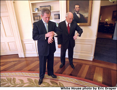 President Bush and Vice President Dick Cheney look at their watches in the Oval Office following the swearing-in ceremony for Sec. Colin Powell. White House photo by Eric Draper.