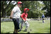 A player for the Thurmont Little League Civitan Club of Frederick Challengers of Thurmont, Md., is accompanied to first base by a South Lawn buddy Sunday, July 30, 2006, at the White House Tee Ball on the South Lawn game against the Shady Spring Little League Challenger Braves of Shady Spring W. Va.