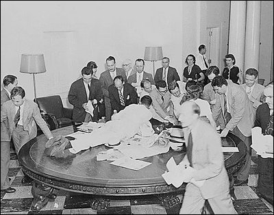 Reporters jump over tables in the White House to pick up press releases about the Japanese surrender, August 14, 1945.