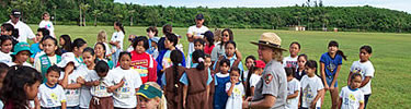 A crowd of children and a park ranger prepare for a day of fun on the edge of a large field