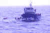 A fishing vessel with several people on deck.  A Coast Guard motor lifeboat is along side.
