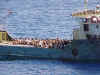 A frighter with rows of PRC migrants sitting on deck.