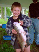 A young boy holding a fish he caught at a Fishing Week event Credit: USFWS