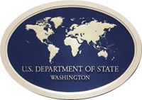 Sign hanging in briefing room at U.S. Department of State: White silhouette of continents on blue oval background with cream-colored oval frame