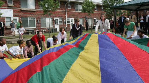 Mrs. Laura Bush joins the children and staff of the Meadowbrook Collaborative Community Center in playing with a colorful parachute during her visit to the facility Tuesday, June 6, 2006 in St. Louis Park, Minn. White House photo by Shealah Craighead
